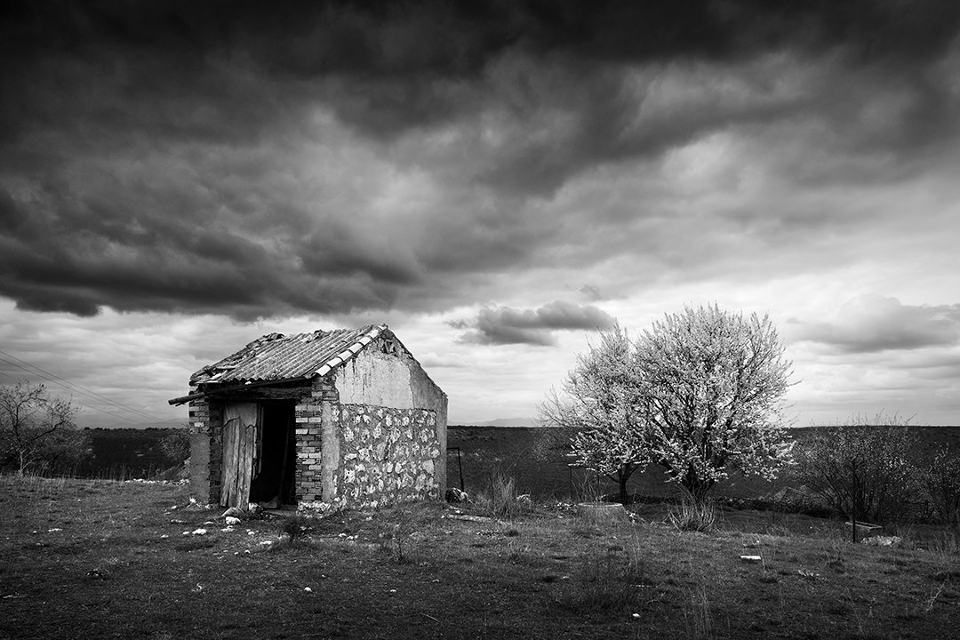 A small stone building beneath dark clouds.
